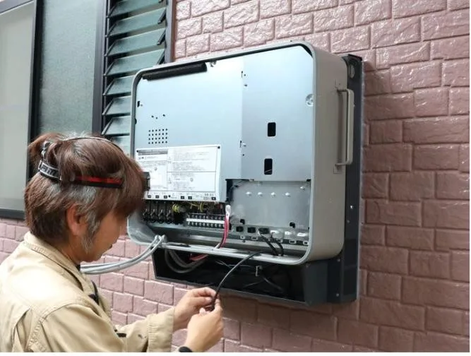 家の外壁に取り付けた蓄電池の機器を配線する社員