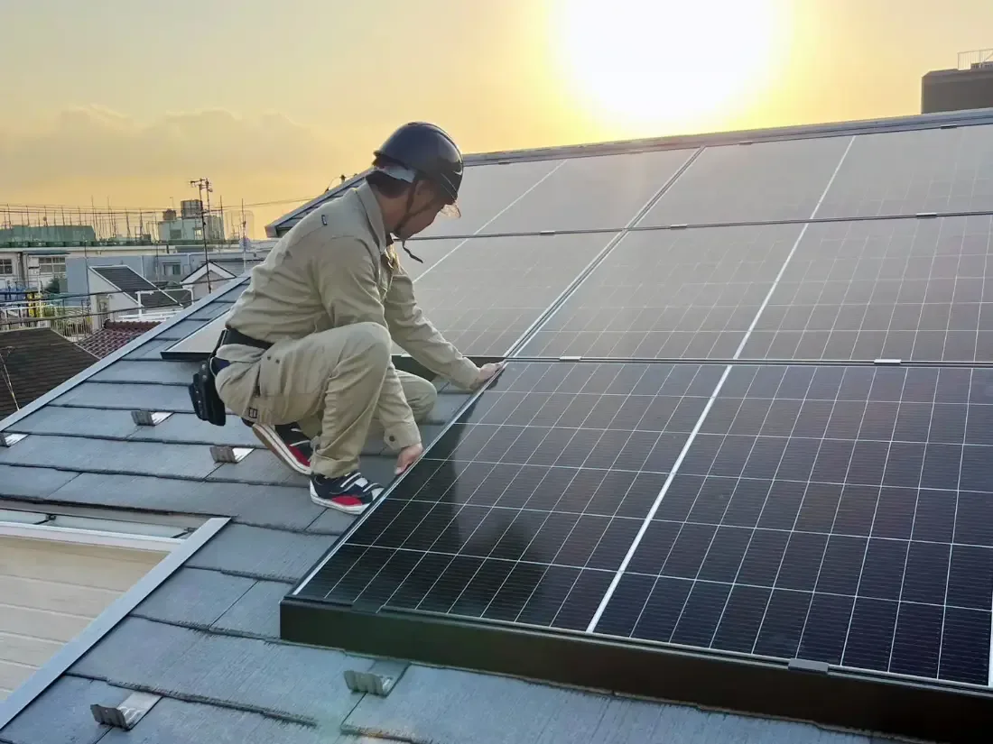 屋根の上で太陽光パネルを取り付ける社員